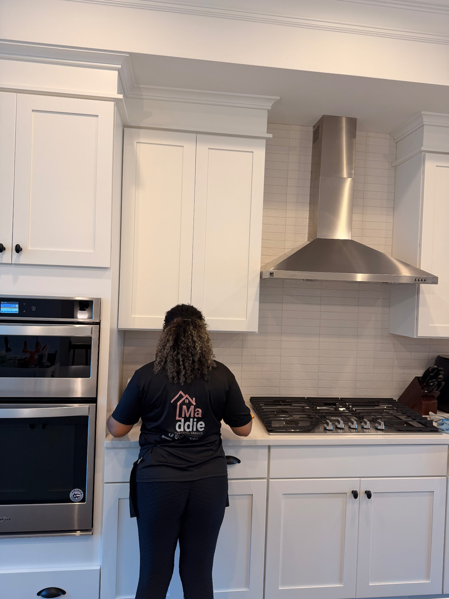 Maddie Cleaning Service cleaner in a branded shirt wiping down a kitchen counter